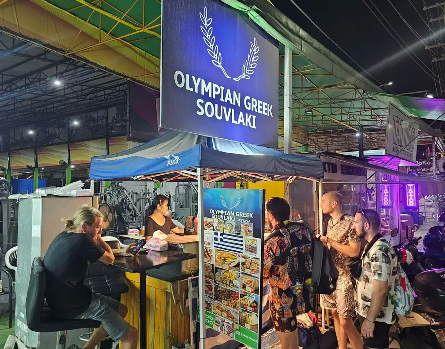 The Olympian Greek Souvlaki booth at night with customers queuing